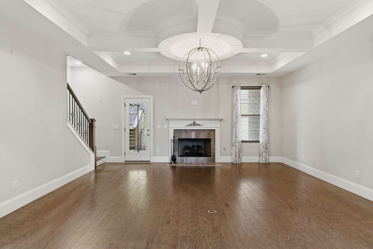 Open living room with a gas fireplace and a stylish high tray ceiling.