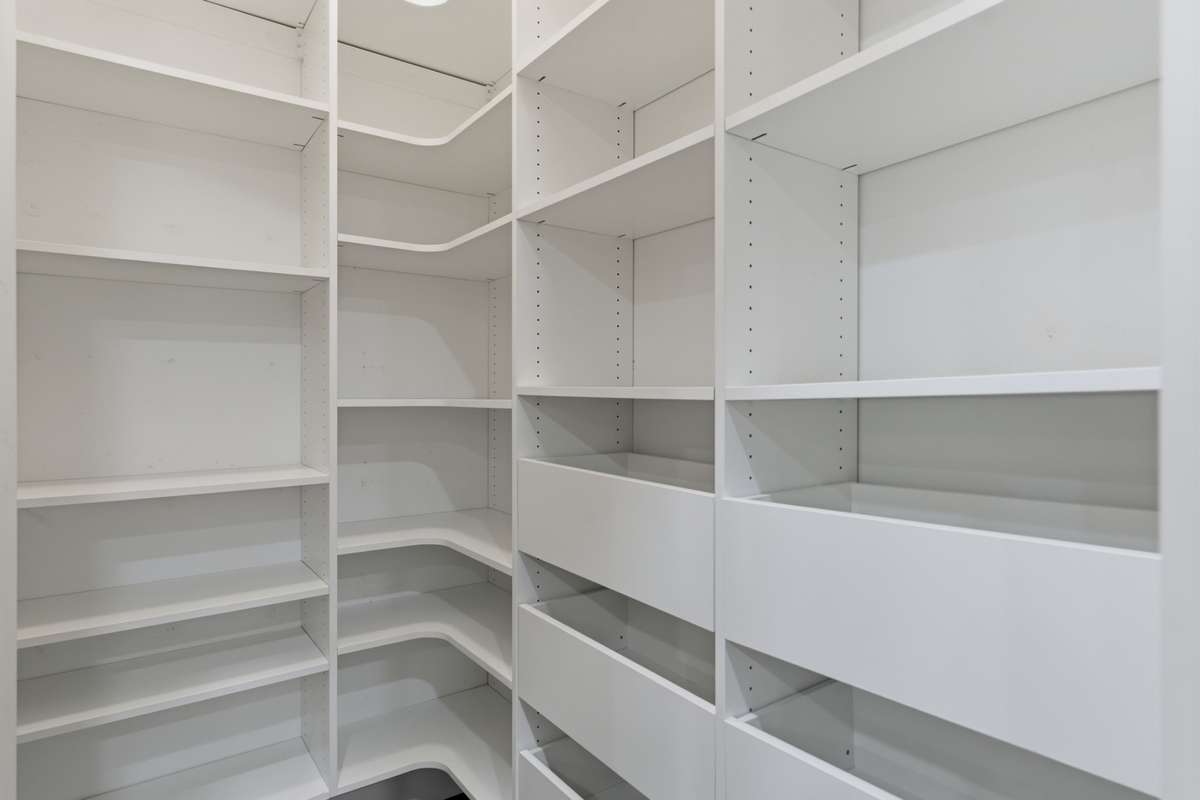 A spacious walk-in pantry equipped with a built-in shelf, facilitating convenient storage.