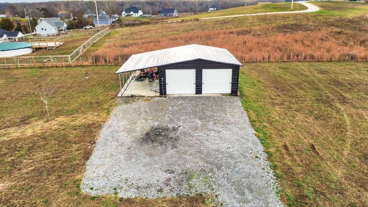 Detached shop features a gravel parking area and a covered porch with an overhang for added functionality.