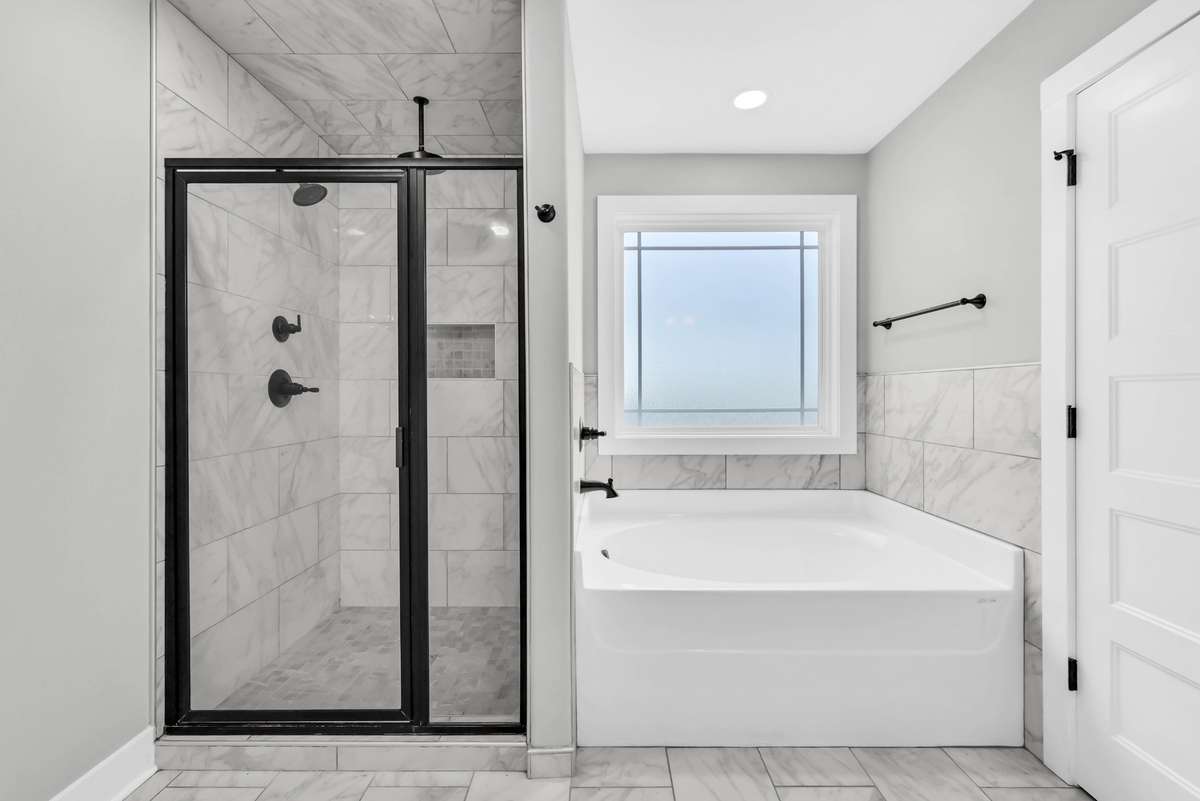 En suite bath includes a beautifully tiled shower with a glass door and a spacious soaking tub for unwinding.