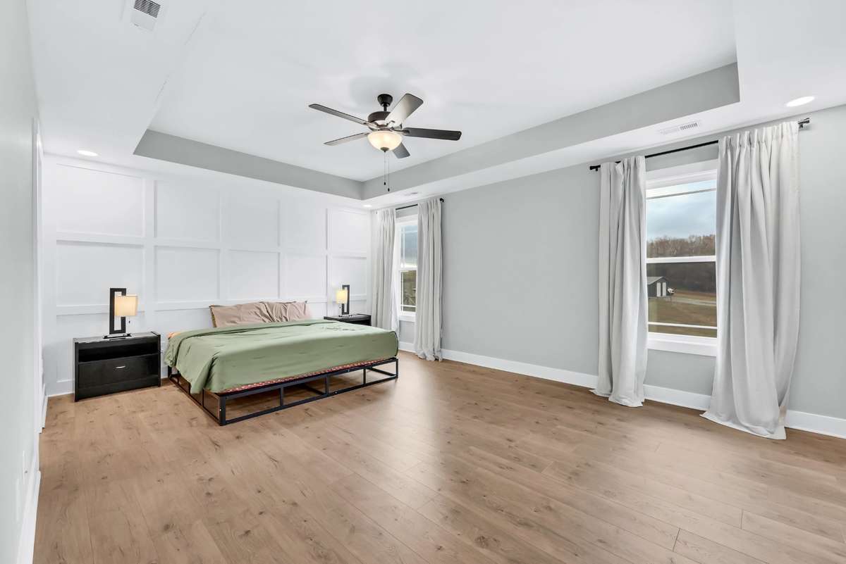 The primary bedroom offers a trey ceiling, stylish accent wall, and warm wood flooring for an inviting retreat.