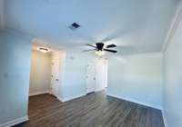 Living room filled with natural light, featuring durable LVP flooring and a ceiling fan for added comfort.
