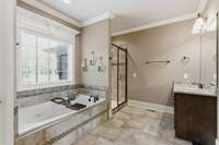 The primary bath features a tub that has a window overlooking the private backyard. It has 2 vanities, a tiled shower, and a separate water closet for privacy.