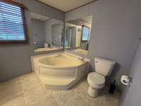 Primary bath featuring a corner garden tub complete with corner mirrors.