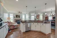 Pendant lighting over the two tier kitchen island featuring sink, dishwasher and granite countertop 