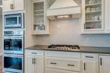 Upgraded double ovesn, built in microwave, gas cooktop, glassfront cabinets, and custom hood