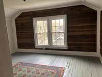 Upstairs bedroom, plank flooring, beadboard paneling and sheetrock walls.