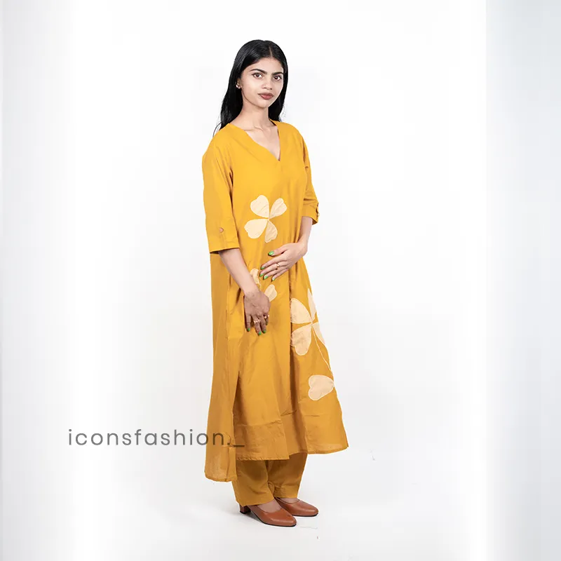 Women-wearing-a-mustard-yellow-A-line-kurta-set-with-floral-applique-work-three-quarter-sleeves-and-matching-pants