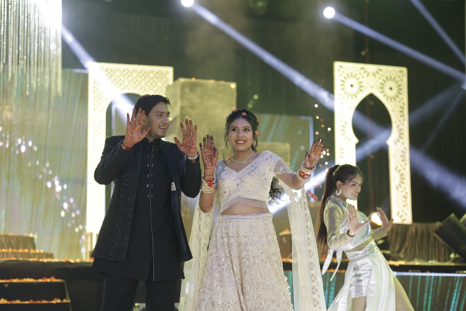 The couple dancing on stage under beams of light at the sangeet