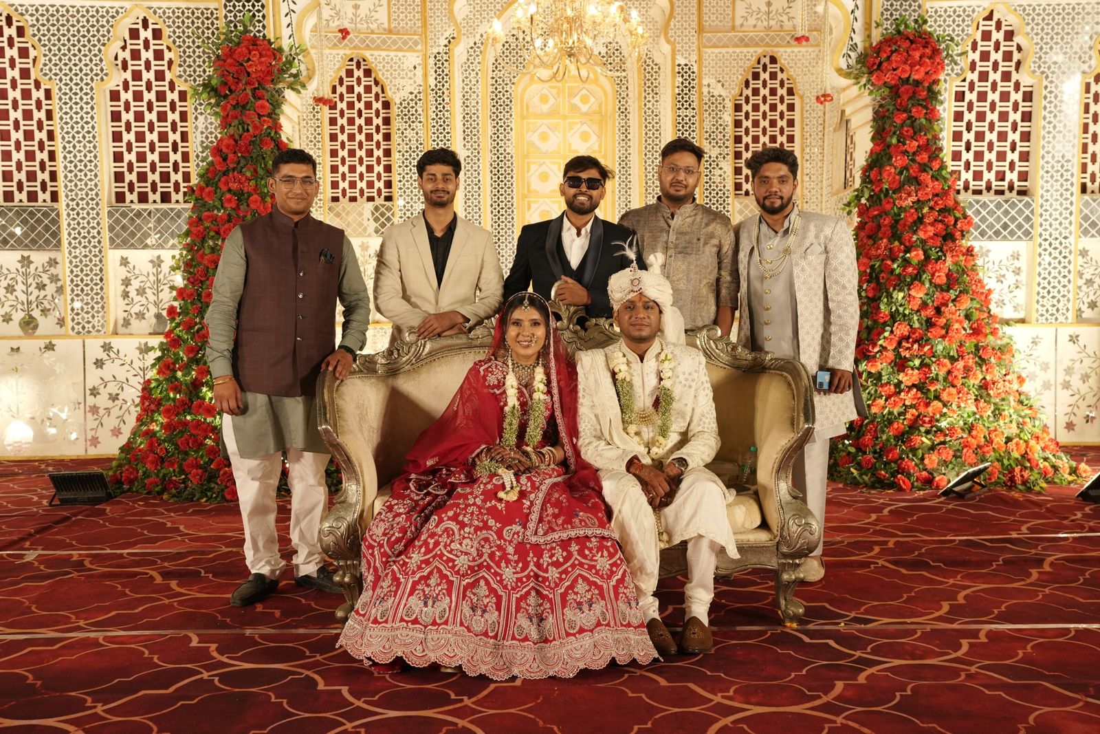 The couple seated on stage with their families at the reception