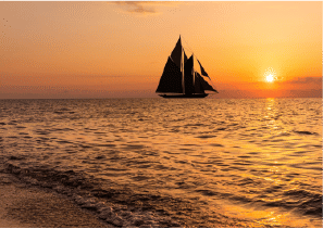 View of Yachtside Marina Residences at sunset with buildings, palm trees, and beach
