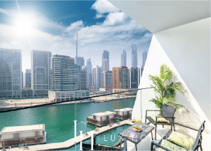 View of Yachtside Marina Residences at sunset with buildings, palm trees, and beach