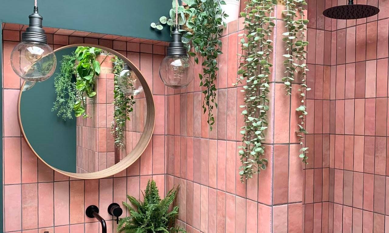 Vibrant modern style bathroom with pink tiles and globe pendants with a plant