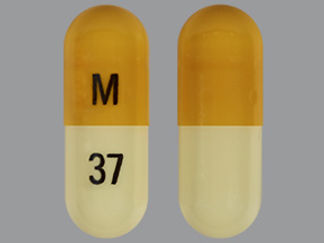 Esto es un Cápsula imprimido con M en la parte delantera, 37 en la parte posterior, y es fabricado por None.