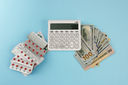Pills, a stack of banknotes, and a calculator