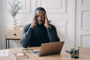 Concerned young man suffering from a headache at his workplace
