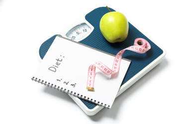 A dieting concept with an apple and a scale on white background