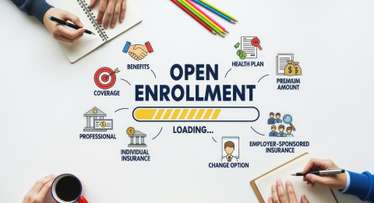 Open Enrollment concept with a loading bar, benefits, coverage, and various insurance options on a white desk