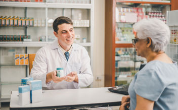 A pharmacist giving advice to an older patients who is asking questions about their prescription