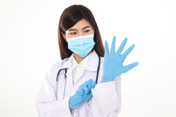 A physician wearing a mask and gloves to prevent infection