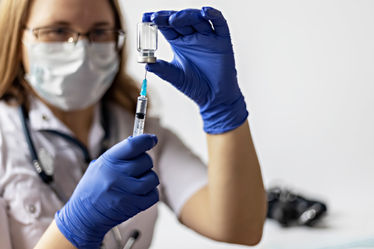 Female medical provider draws vaccine into syringe 