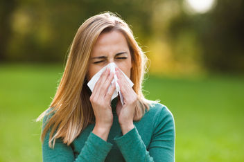 Woman blowing her nose outdoors