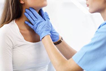 A female physician checking her patients thyroid