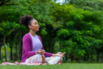 African American woman relaxingly practicing meditation in the forest to attain happiness from inner peace wisdom for healthy mind