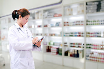 A woman pharmacist in a drug store checking the inventory