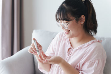 A woman using lancet on finger for checking blood sugar level by glucose meter