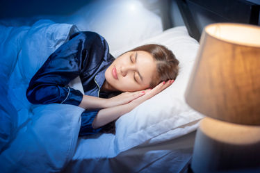 A woman sleeping in bed with the light on