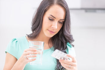 Woman holding blister pack with pills and reading medical instructions