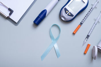 Blue ribbon and glucometer, medical supplies on color background top view with copy space