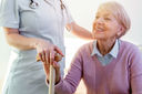 Elder lady sitting on the couch with wooden walking stick and smiling