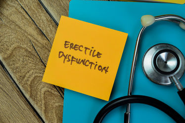 Erectile dysfunction written on a sticky notes with stethoscope isolated on wooden table