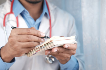 A doctor hand writing a prescription for a patient