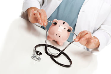 Physician holds a stethoscope to the ears of a pink piggy bank