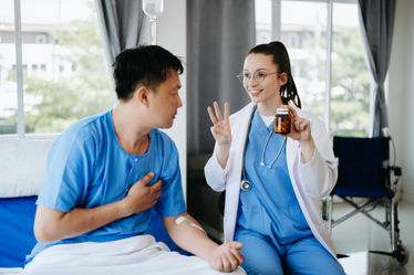 Female doctor in white suit take notes while discussing with a male patient