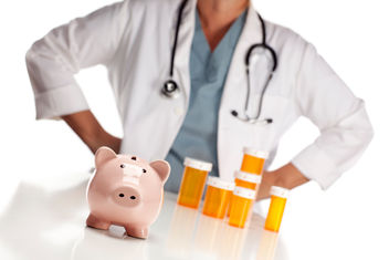 Physician in a white coat standing behind medicine bottles and piggy bank