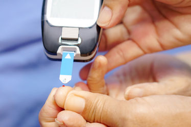 Doctor wearing gloves using lancet on finger for checking blood sugar