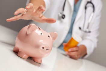 Doctor holding a prescription bottle and reaching for a piggy bank