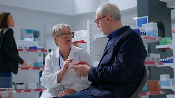 Elderly pharmacist in drugstore with senior patient discussing prescription options