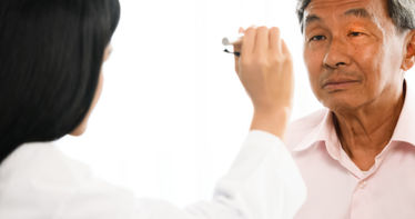 Female physician checking male patient's eyes at hospital room