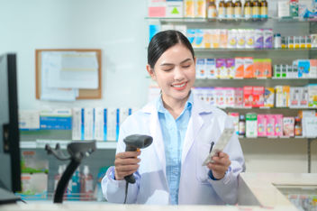 Female pharmacist scanning barcode on a medicine box at the pharmacy