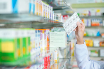 Female pharmacist reaching for medication in a pharmacy