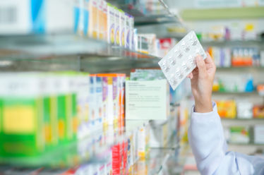 Female pharmacist reaching for medication in a pharmacy