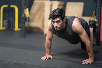 A young athletic man doing push ups in a gym in order to stay fit