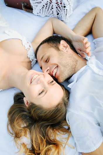 A happy couple laying down outdoors and smiling at each other