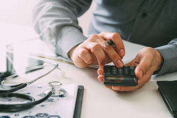 A doctor using a calculator to show cost savings