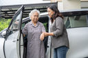 Caregiver helping elderly woman out of the car